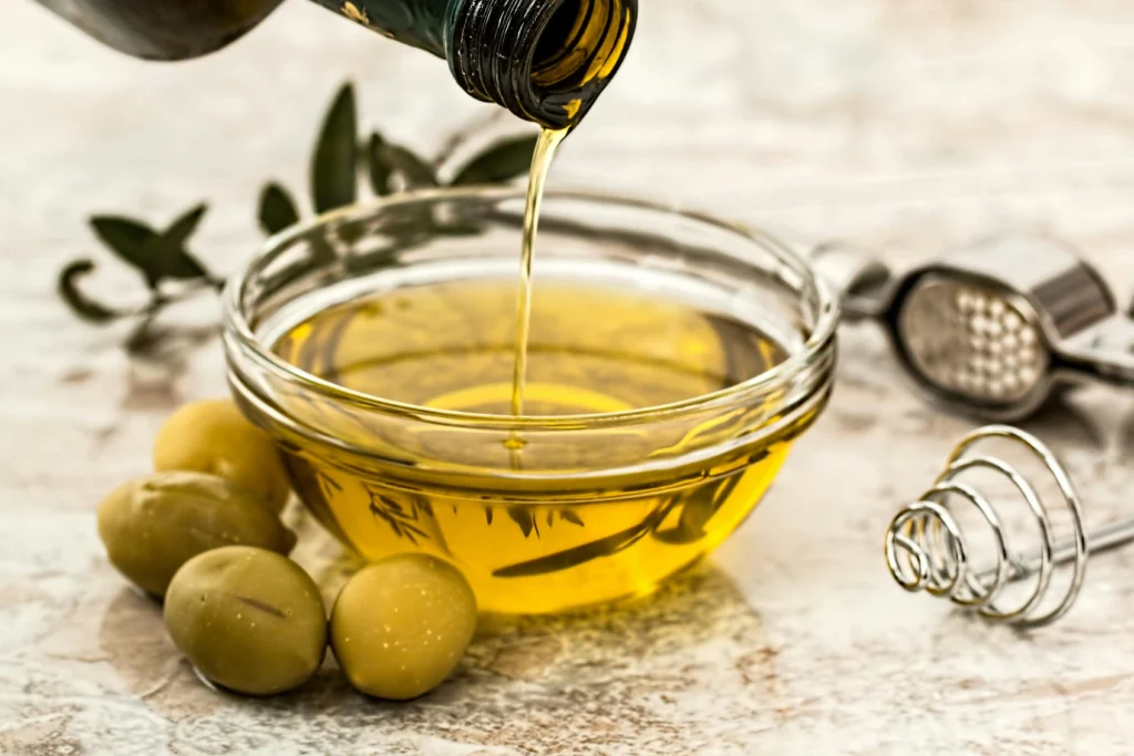 extra virgin olive oil being poured into bowl with olives close up