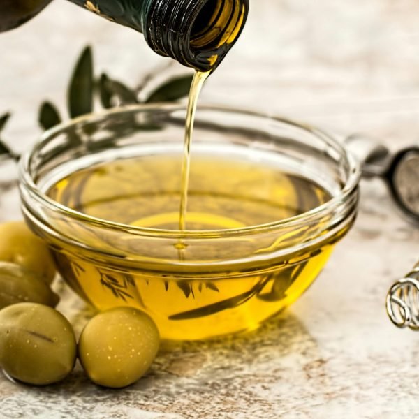 extra virgin olive oil being poured into bowl with olives close up